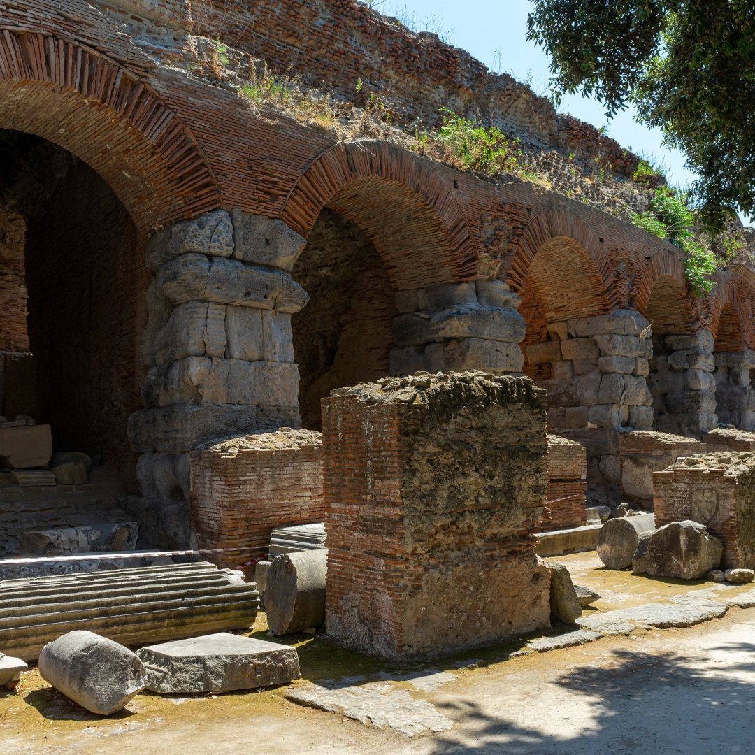 Brick and stone radial arches of the Flavian Amphitheater at Pozzuoli with fallen column fragments on the ground