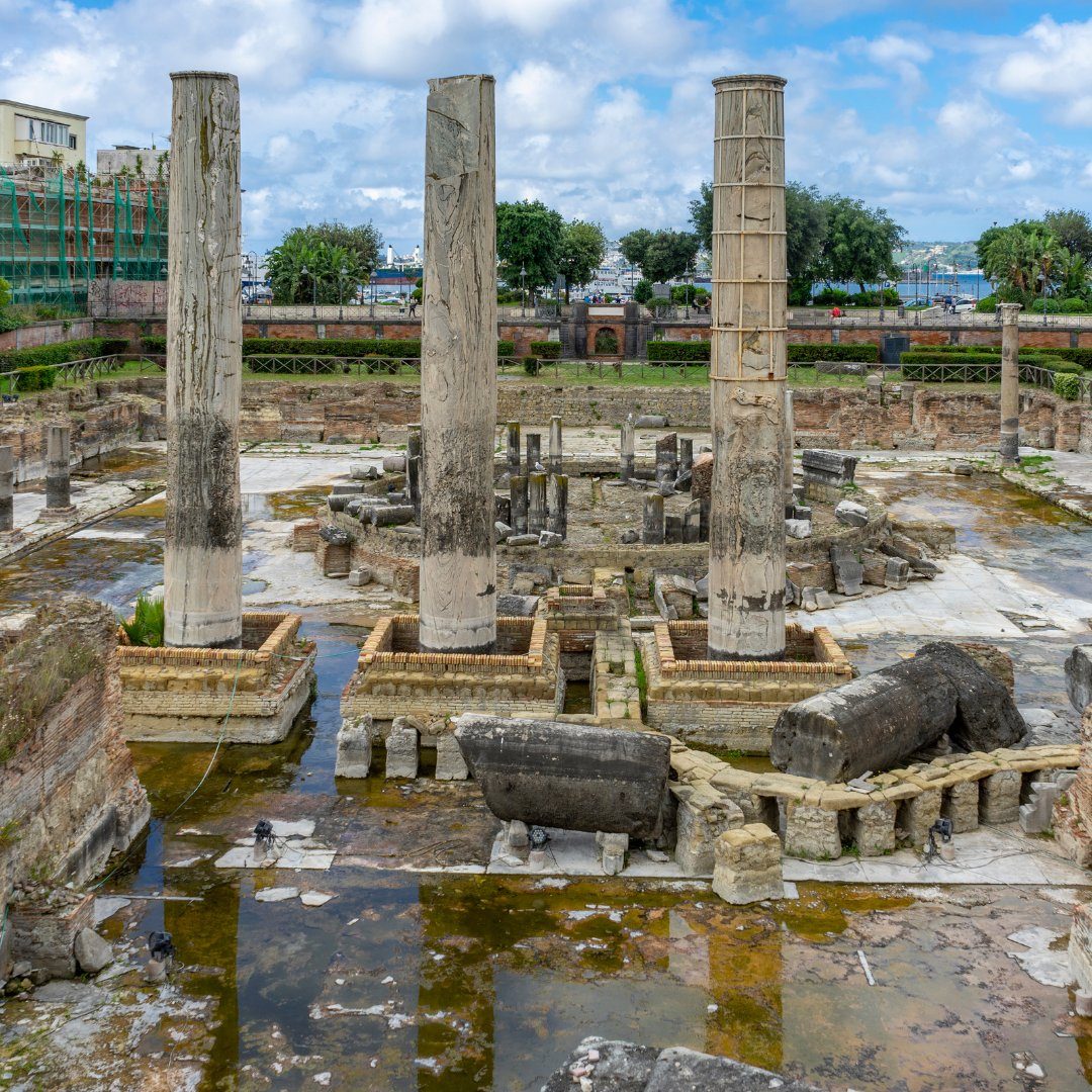 Three tall marble columns of the Macellum, the so-called Temple of Serapis, rising from the waterlogged Roman market in Pozzuoli